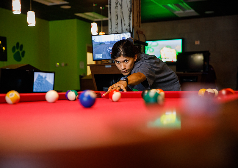 student playing billiards in game room